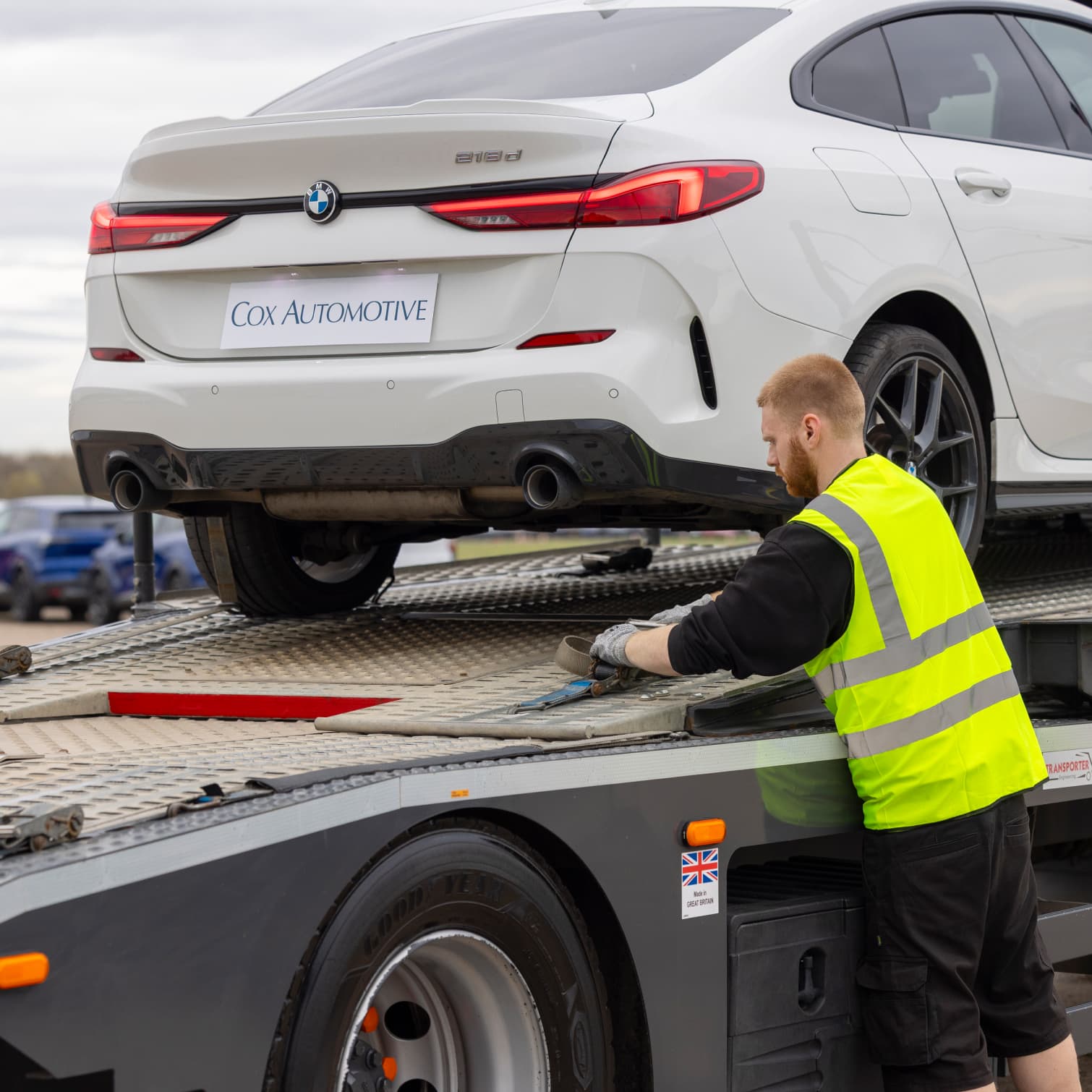 A man strapping down a car from cox automotive.