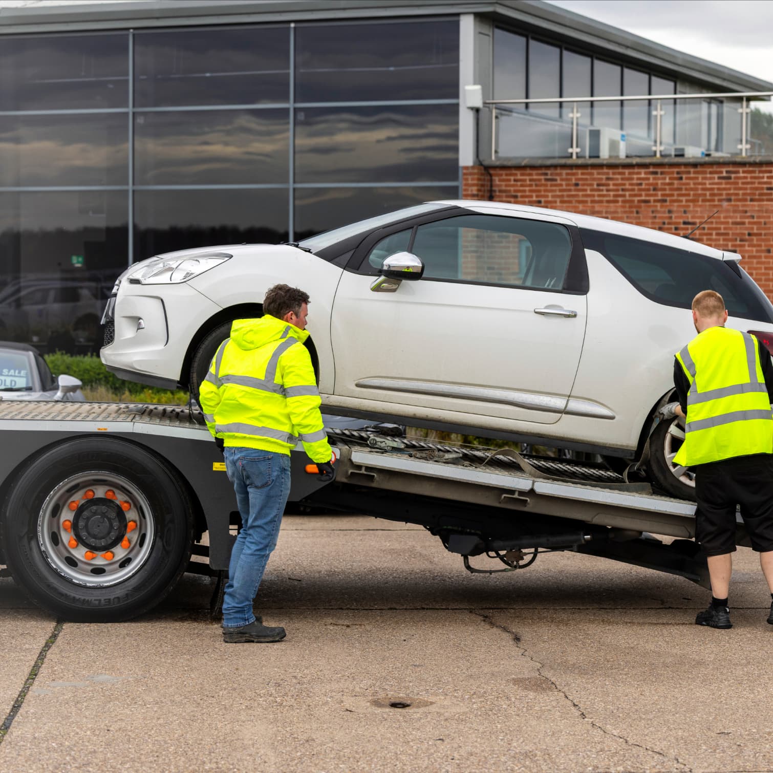 Two people loading a car onto a transporter.
